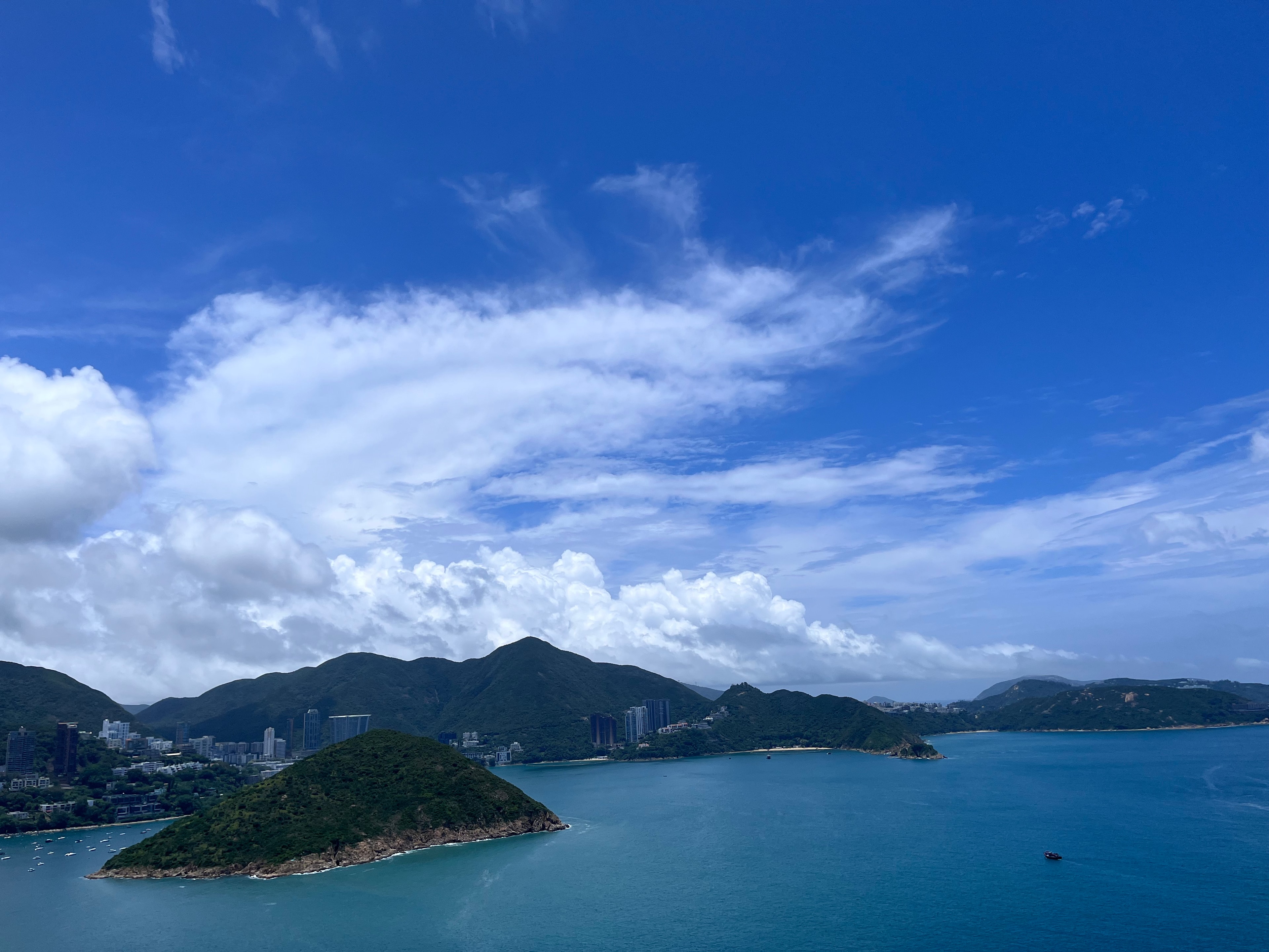 Coastal bay with green islands under vivid blue sky and white clouds
