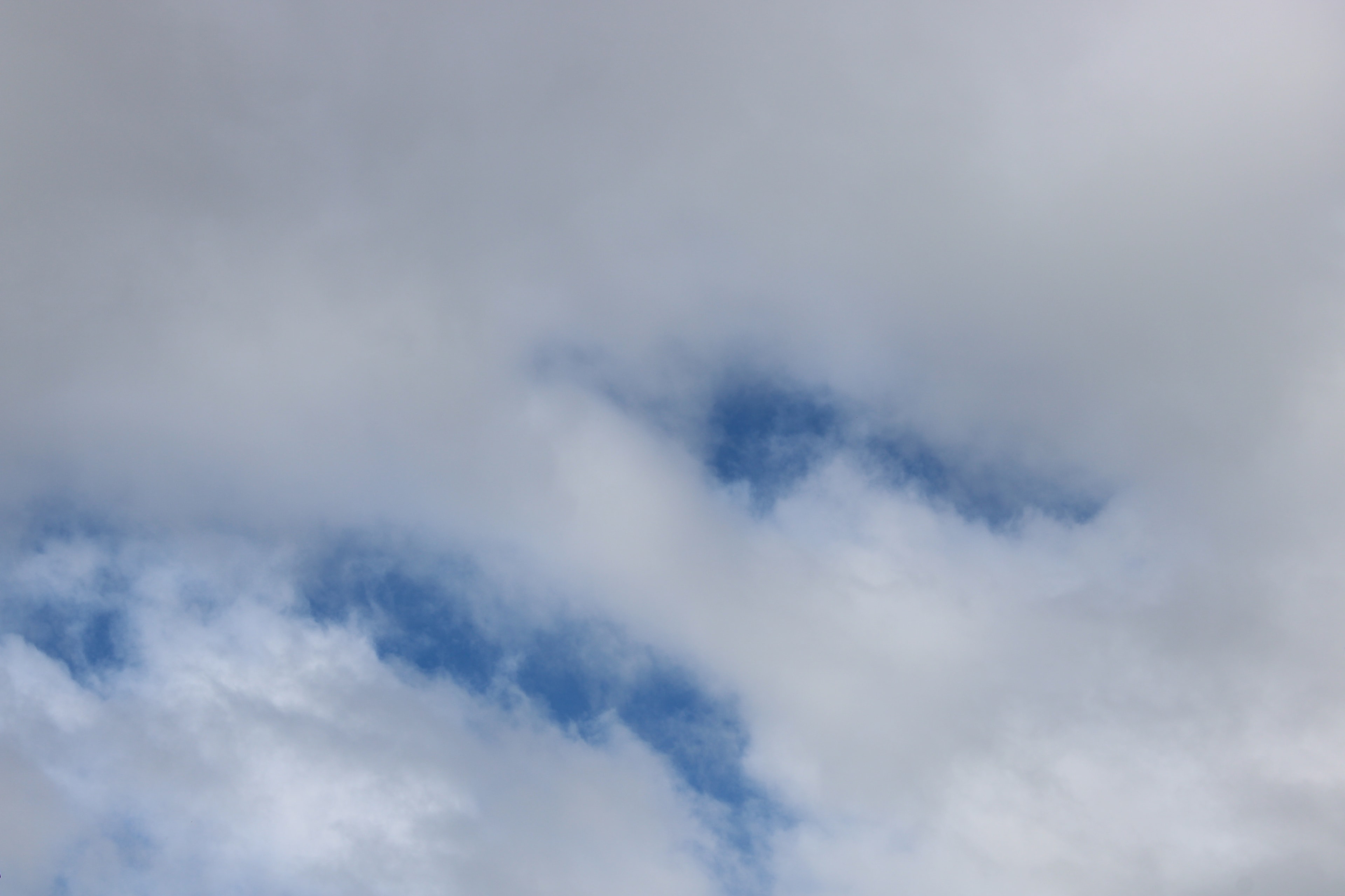 Soft layered clouds with blue sky peeking through