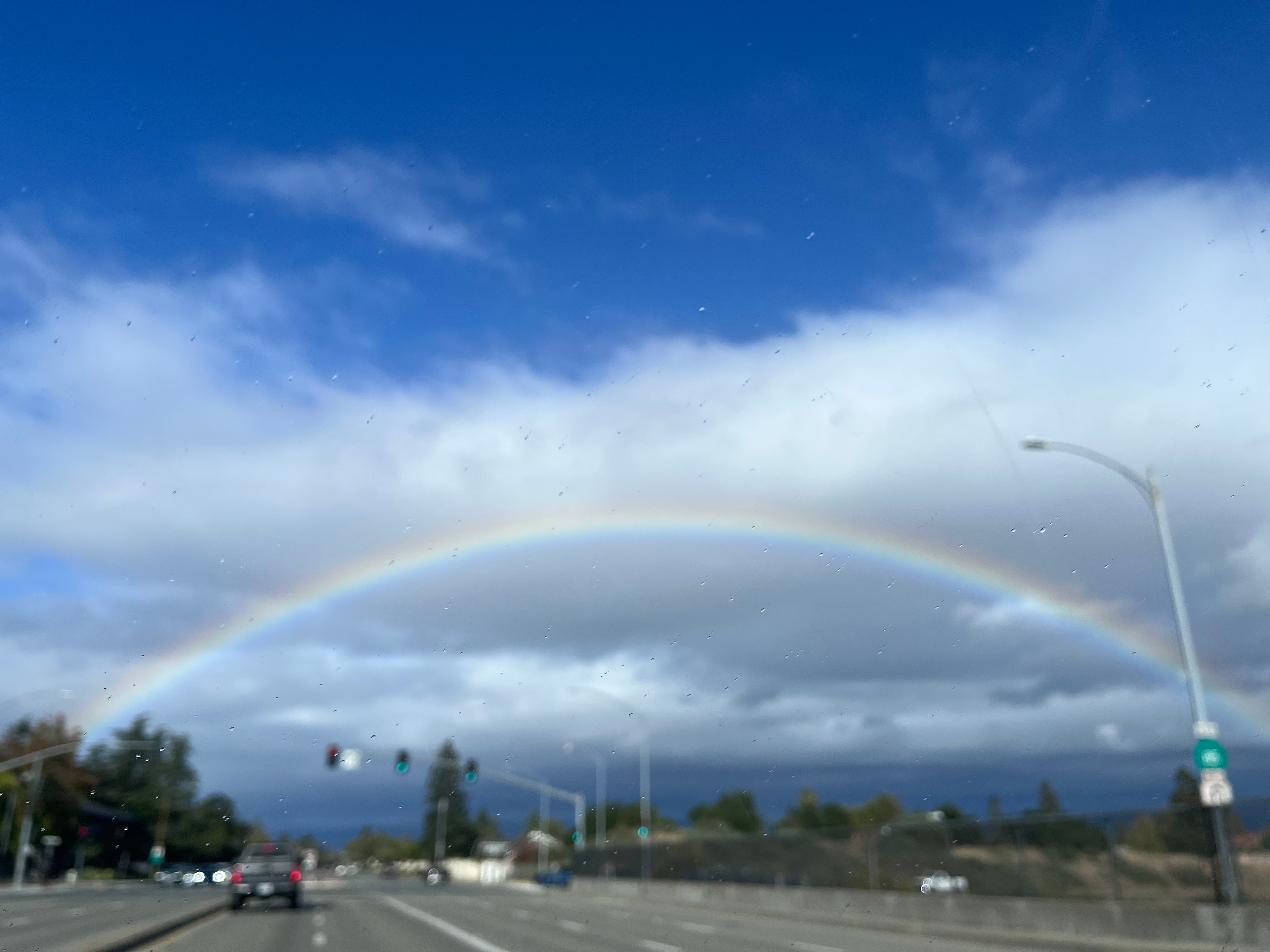 Full rainbow arc over a highway under blue sky